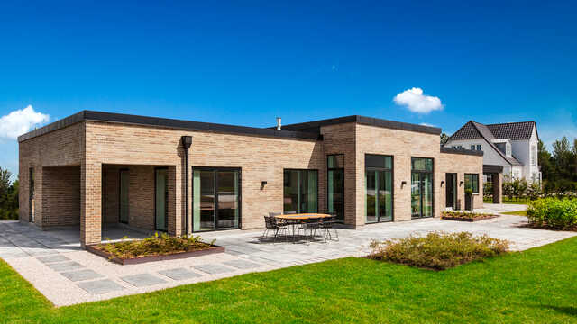 Vælg fladt tag hvis I ønsker funktionalisme og minimalisme i arkitekturen. Her er gennemført funkisarkitektur med fladt tag i flere niveauer. Murkronen er udført i sort zink og matcher flot facadernes vinduespartier.